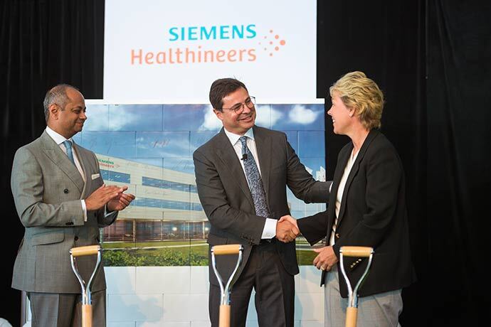 Franz Walt, president of Laboratory Diagnostics, Siemens Healthineers shakes hands with Lisa Davis, chair and CEO of Siemens Corporation and member of the managing board of Siemens AG as Michael Sen, member of the managing board of Siemens AG and Siemens Healthcare GmbH Supervisory Board chairman, looks on during a groundbreaking ceremony Friday, June 30, 2017 in Walpole, Massachusetts.